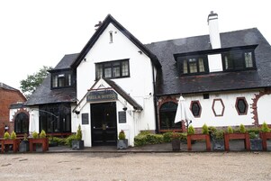 A traditional building with a black roof, white walls, and a sign reading "BELL & BOTTLE".