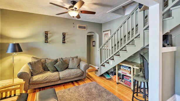 A living room with a sofa, a coffee table, a floor lamp, a ceiling fan, and a staircase. - Home w/ Gas Grill - Walk to Bisbee Brewing Co (Bisbee)