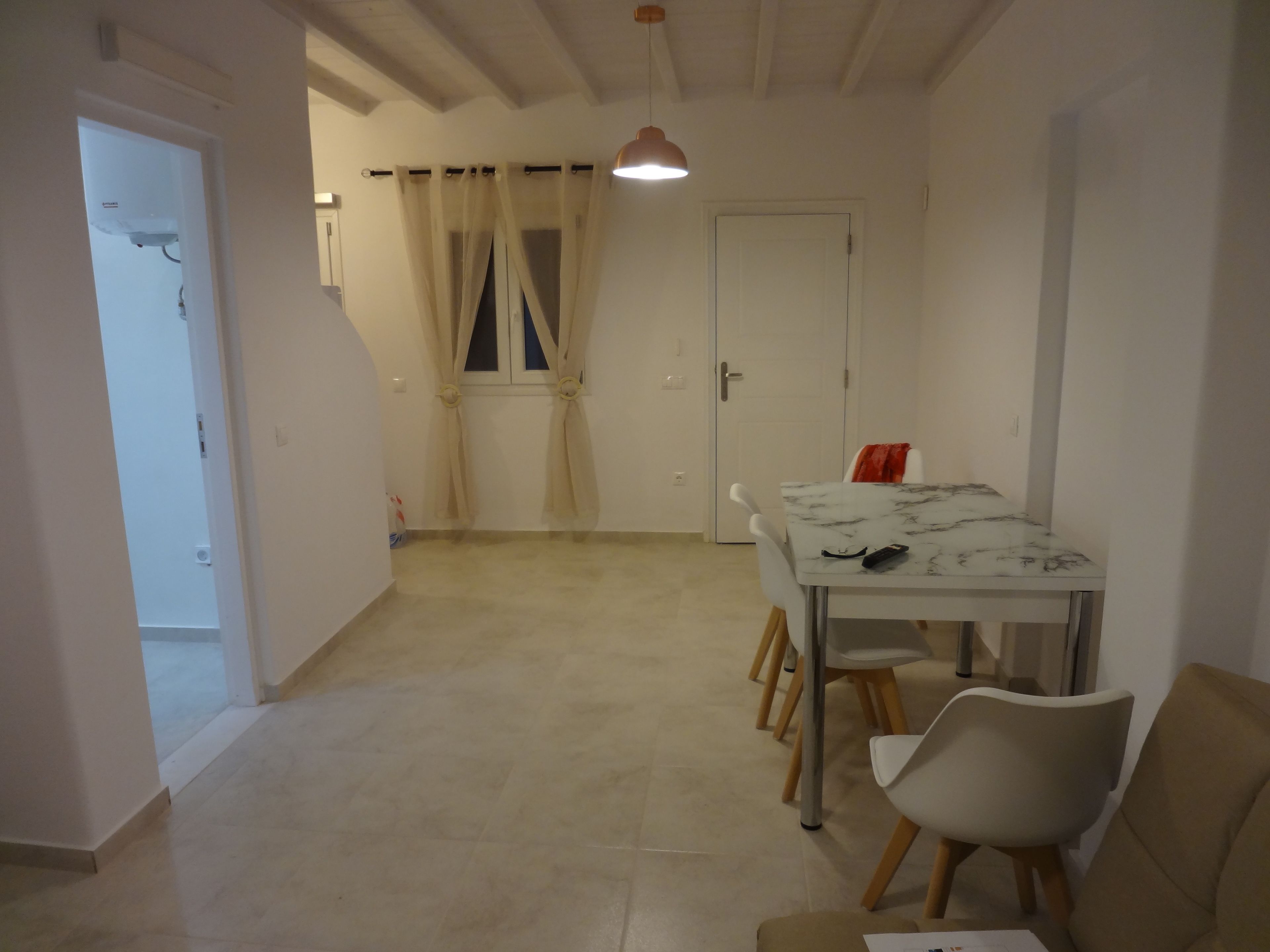 A dining area with a table and chairs, a door, and a window with curtains.