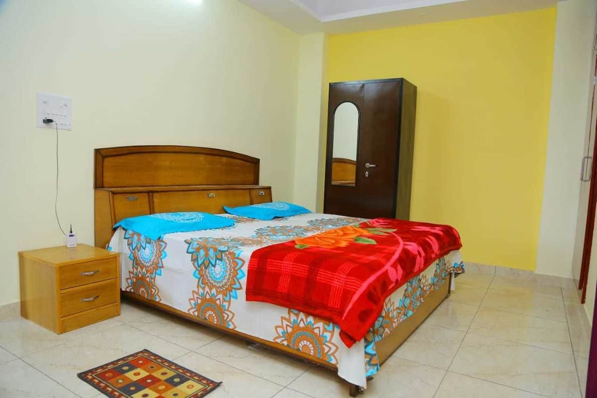 A bedroom with a bed, a nightstand, a wardrobe, and a mirror.