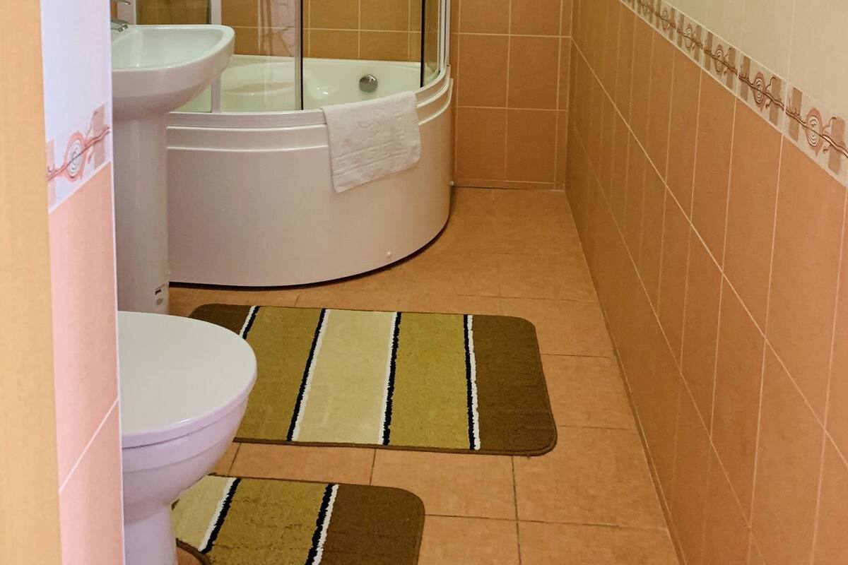 Un baño con ducha envuelta en vidrio, un lavabo e inodoro.