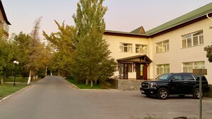 A two-story building with a green roof, a driveway, and a black SUV parked in front. - Hotel Sirdaria (Kyzylorda)