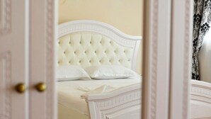 A room with a bed featuring a tufted headboard and white bedding. - Hotel Sirdaria (Kyzylorda)