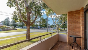 A balcony with a view of a street, a brick wall, and a small table. - Seahorse 4 - Ground floor, and in the most requested area of Tuncurry! (Tuncurry)