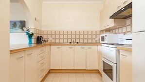 A compact kitchen with a microwave, stove, and a sink. - Seahorse 4 - Ground floor, and in the most requested area of Tuncurry! (Tuncurry)