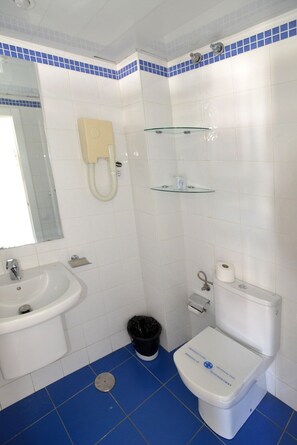 A bathroom with a sink, toilet, and glass shelves. - Apartamentos Arco Iris (San Bartolomé de Tirajana)