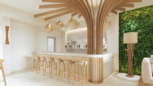 Una cocina moderna con una isla central, taburetes de bar, luces colgantes y una pared verde.