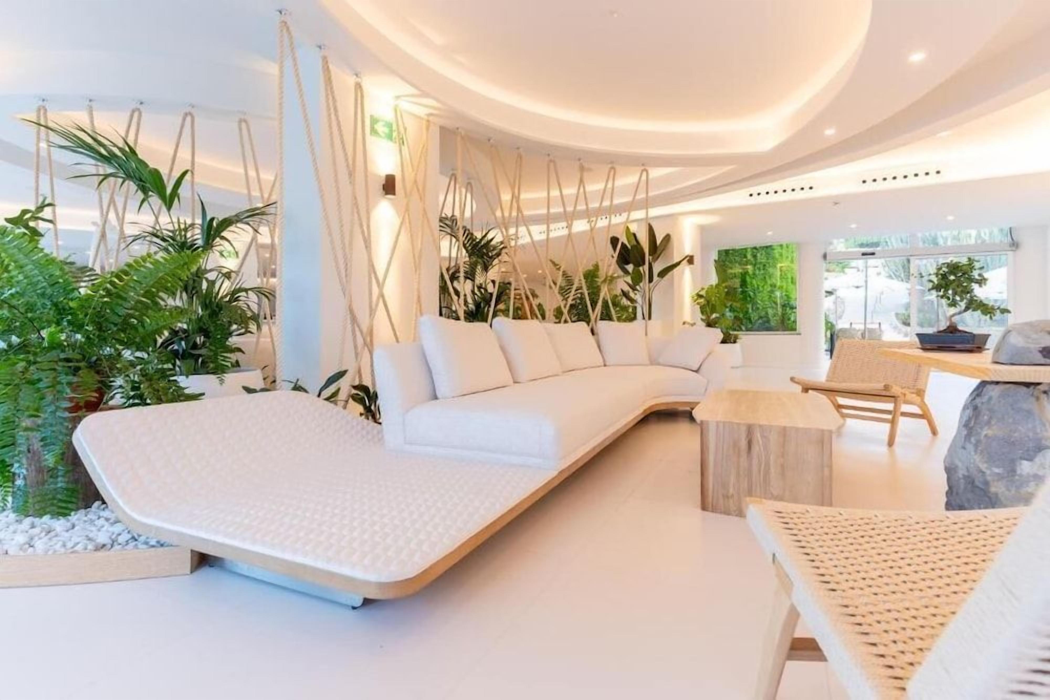 Un intérieur moderne avec un canapé blanc, un fauteuil suspendu et une petite table.