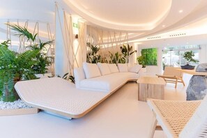A modern interior with a white sofa, a hanging chair, and a small table. - HL Hotel Rondo (San Bartolomé de Tirajana)