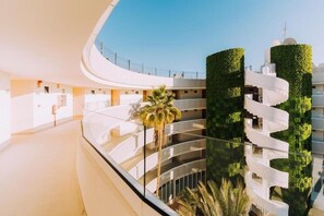 A modern building with a curved balcony, glass railings, and greenery. - HL Hotel Rondo (San Bartolomé de Tirajana)