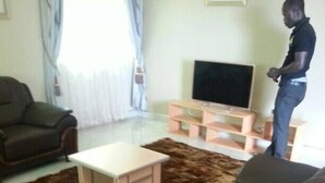 A living room with two sofas, a coffee table, and a TV stand. - MJ Appartments (Accra)