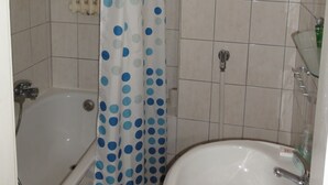A bathroom with a bathtub, a shower, and a sink. - Zimmervermietung Lösken 1 (Duisburg)