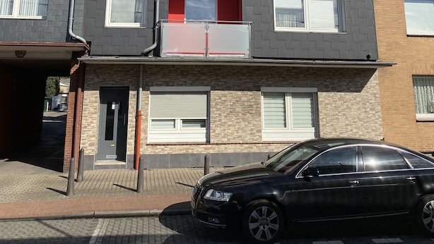 A multi-story residential building with a garage entrance, a black car parked in front, and a clear sky. - Zimmervermietung Lösken 1 (Duisburg)