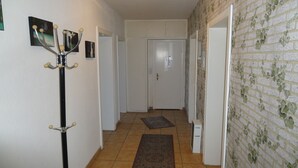 A hallway with a coat rack, a door at the end, and a patterned wall. - Zimmervermietung Lösken 1 (Duisburg)