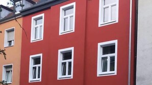 Um edifício vermelho com janelas emolduradas em branco e o número '68' no canto inferior direito.