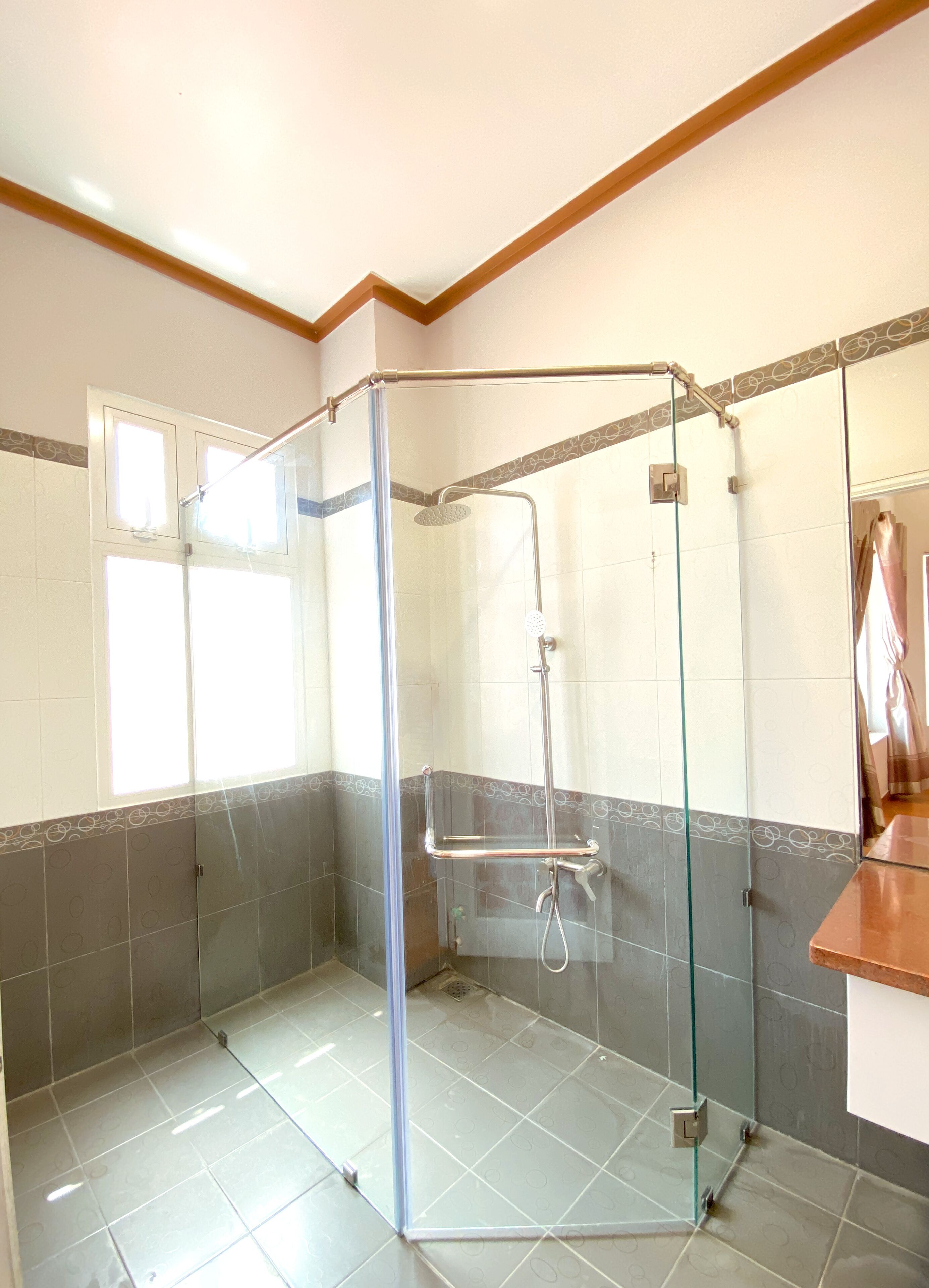 Zona de ducha con puerta de cristal, paredes de azulejos y techo de madera.