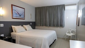 A hotel room with a large bed, a bedside table with a phone, a chair, and a desk. - Allegro Hotel (Goiania)