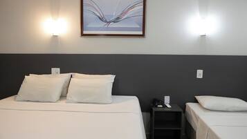 Una habitación de hotel con una cama grande, dos mesitas de noche y un cuadro colgado en la pared.