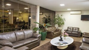 A spacious living area with leather sofas, a coffee table with magazines, and potted plants. - Allegro Hotel (Goiania)