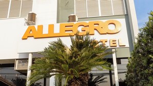 A hotel named 'ALLEGRO' with a modern facade, air conditioning units, and a palm tree in the foreground. - Allegro Hotel (Goiania)