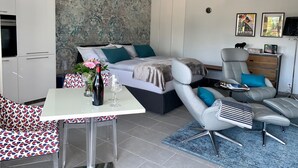 A modern bedroom with a bed, a desk, a chair, and a sofa. - Bijou Lido Golf (Ascona)
