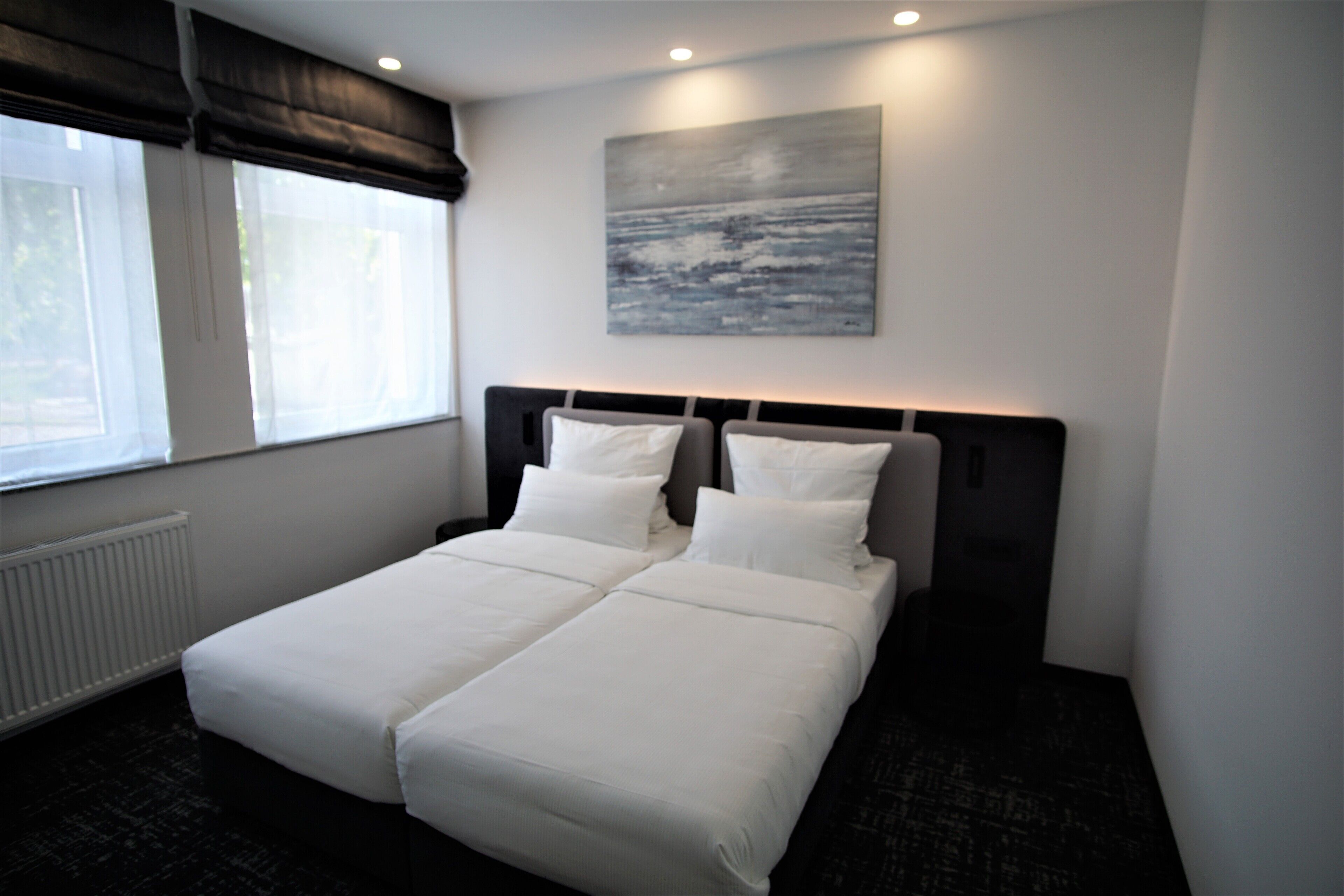 Una cama doble con ropa de cama blanca en una habitación de hotel.