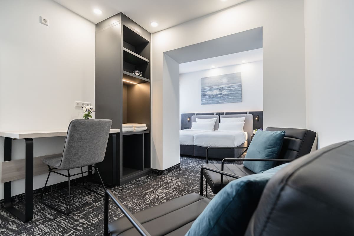 Moderni hotellihuone, jossa on sänky, työpöytä ja tuoli.