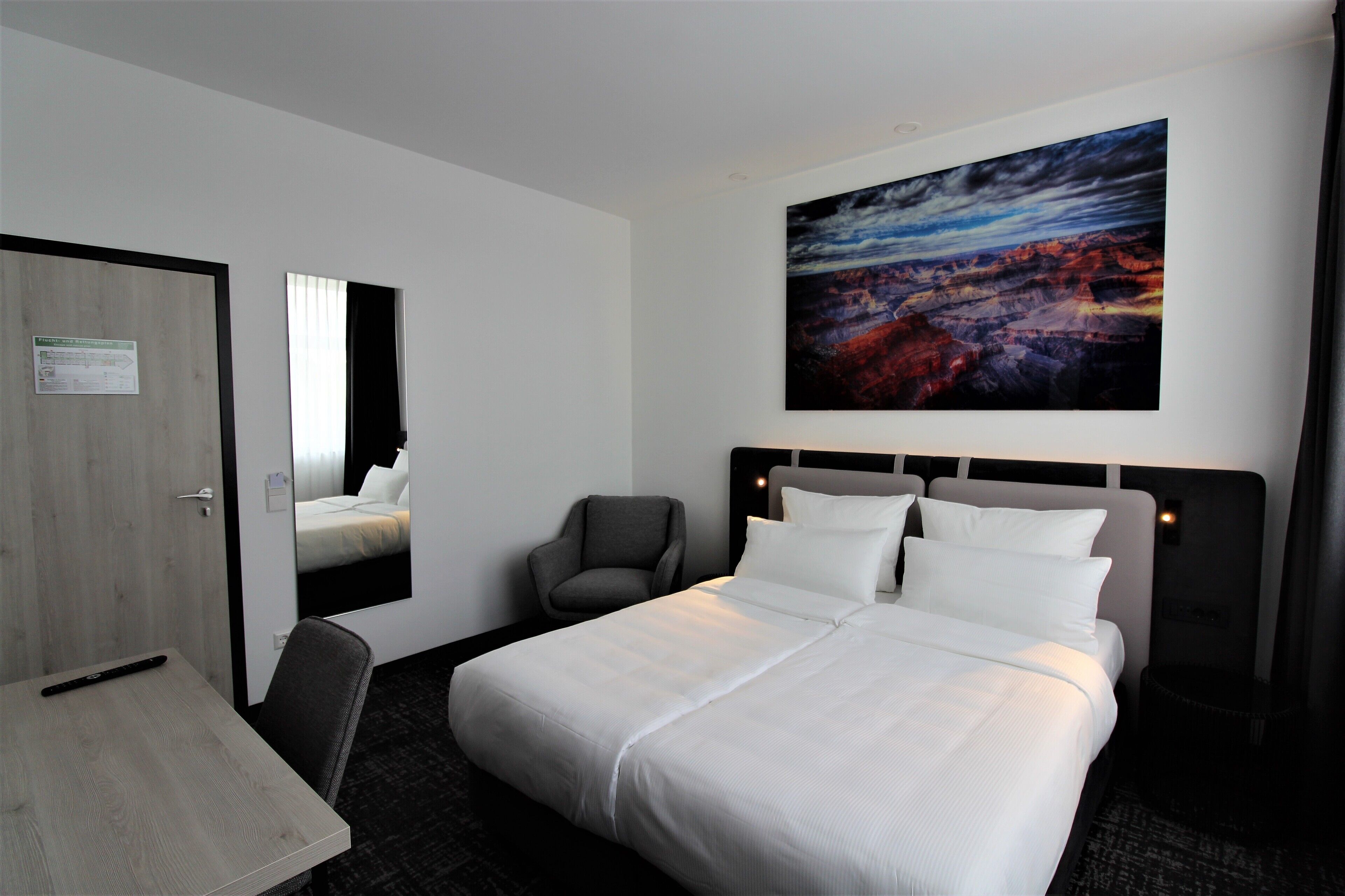 Une chambre d’hôtel avec un grand lit, un bureau, une chaise et un tableau au mur.
