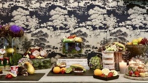 A table with various food items and drinks, including pastries, fruits, and a bottle of champagne.
