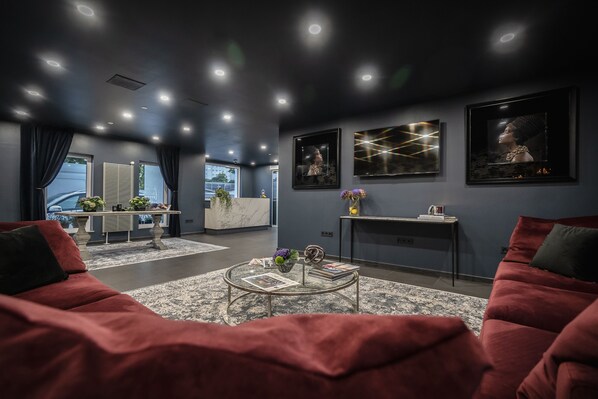 A modern living room with a red sofa, a coffee table with magazines, and artwork on the walls. - Libarty Hotels (Weinstadt)