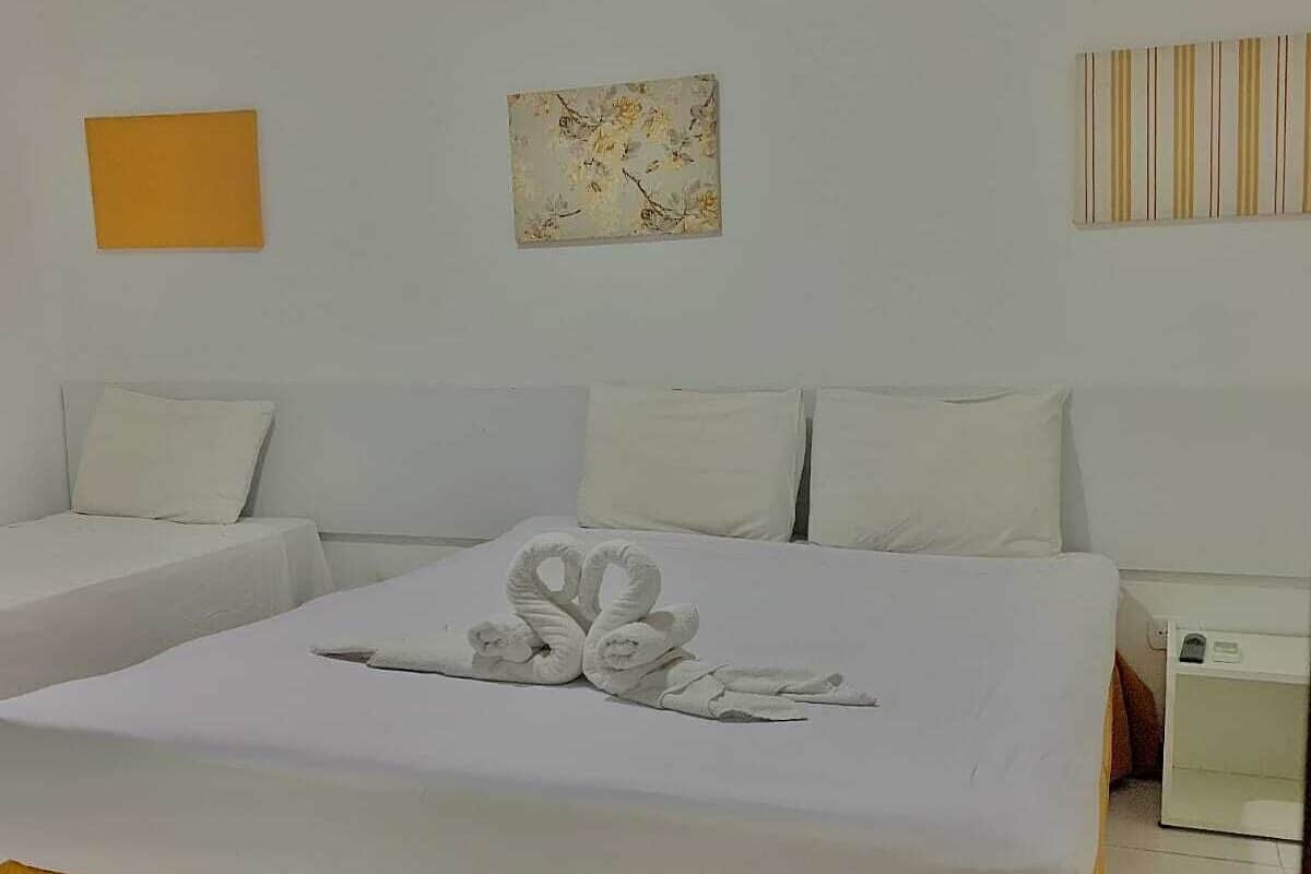 Quarto de hotel com cama, duas mesas de cabeceira e uma obra de arte na parede.