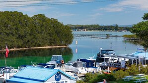 Een jachthaven met aangemeerde boten, een restaurantbar en uitzicht op het omliggende bos en water.