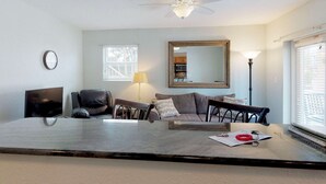 A living room with a ceiling fan, a large mirror, a sofa, a coffee table, and a TV.