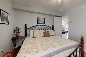 A bedroom with a bed, a nightstand, a lamp, and a painting on the wall.