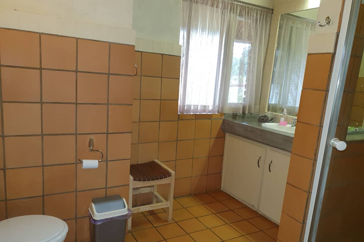 Une petite salle de bain comprenant des toilettes, une poubelle, un lavabo et un miroir.