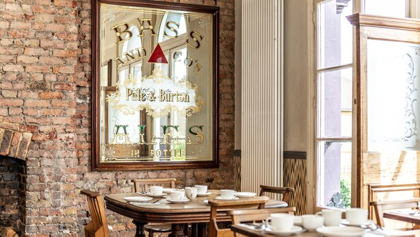 A dining area with a brick wall, wooden furniture, and a framed sign. - The Brownswood (London)