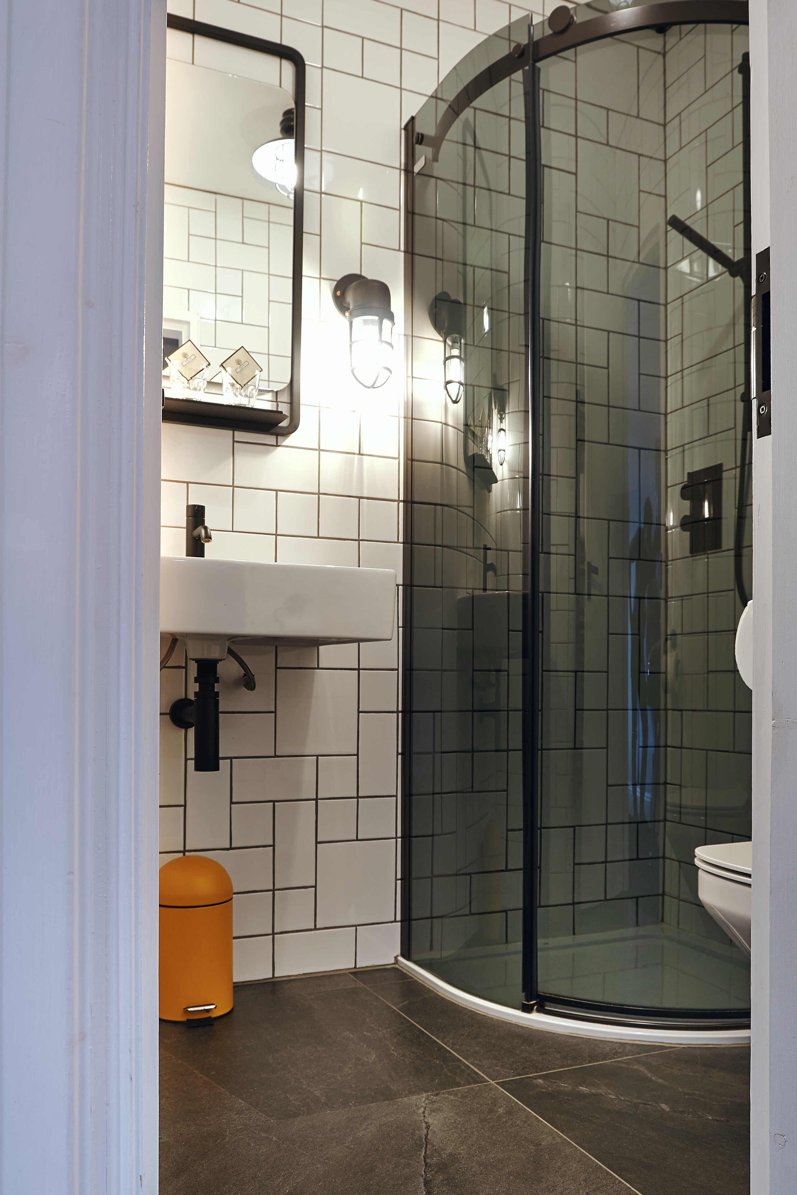 A bathroom with a glass-enclosed shower, a sink with a mirror above it, and a toilet.