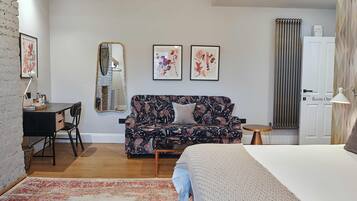 Makuuhuoneessa on sänky, sohva, työpöytä ja tuoli. Seinällä on kaksi kehystettyä kuvaa, peili ja patteri.