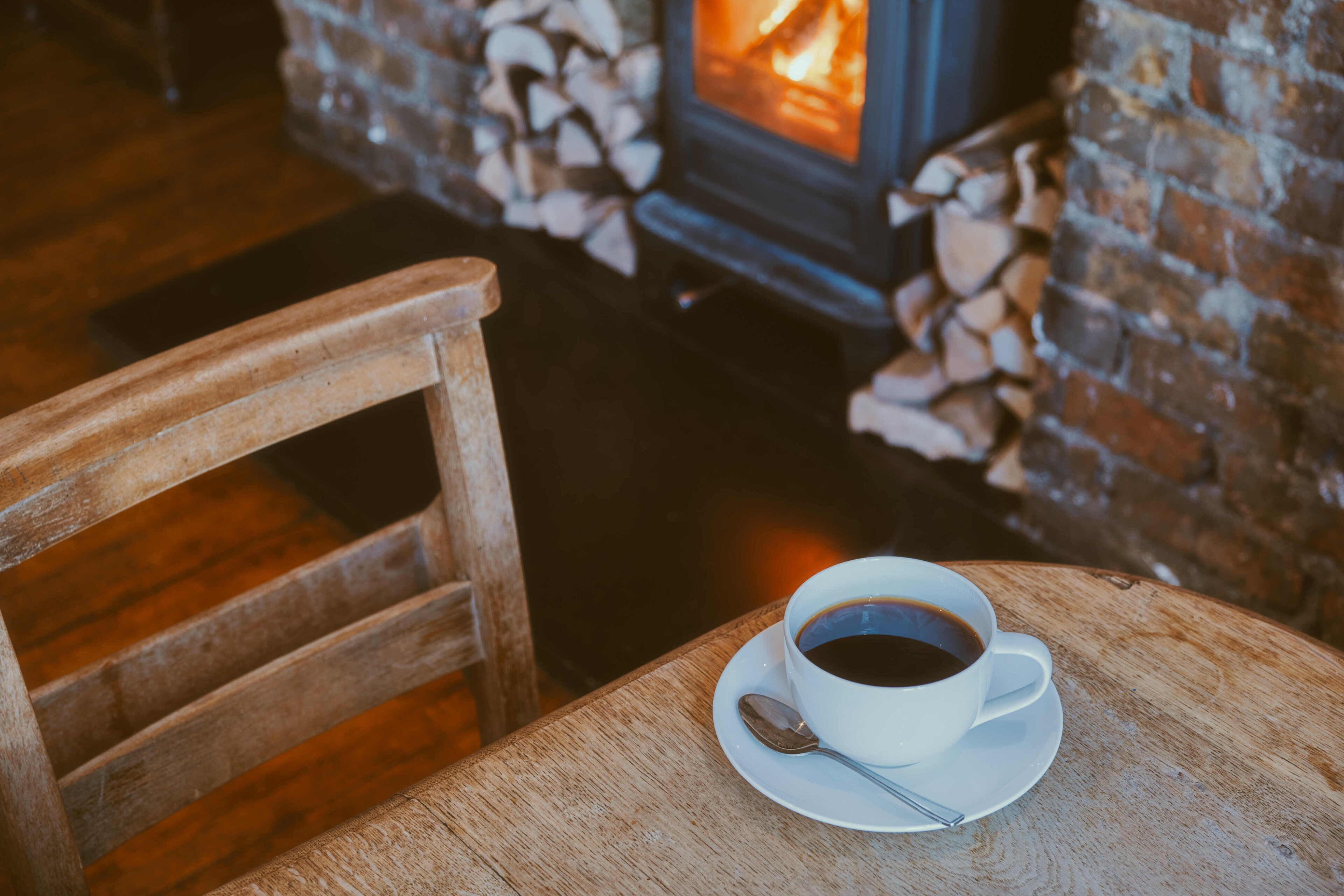 Una silla y una mesa de madera con una taza de café y una cuchara.