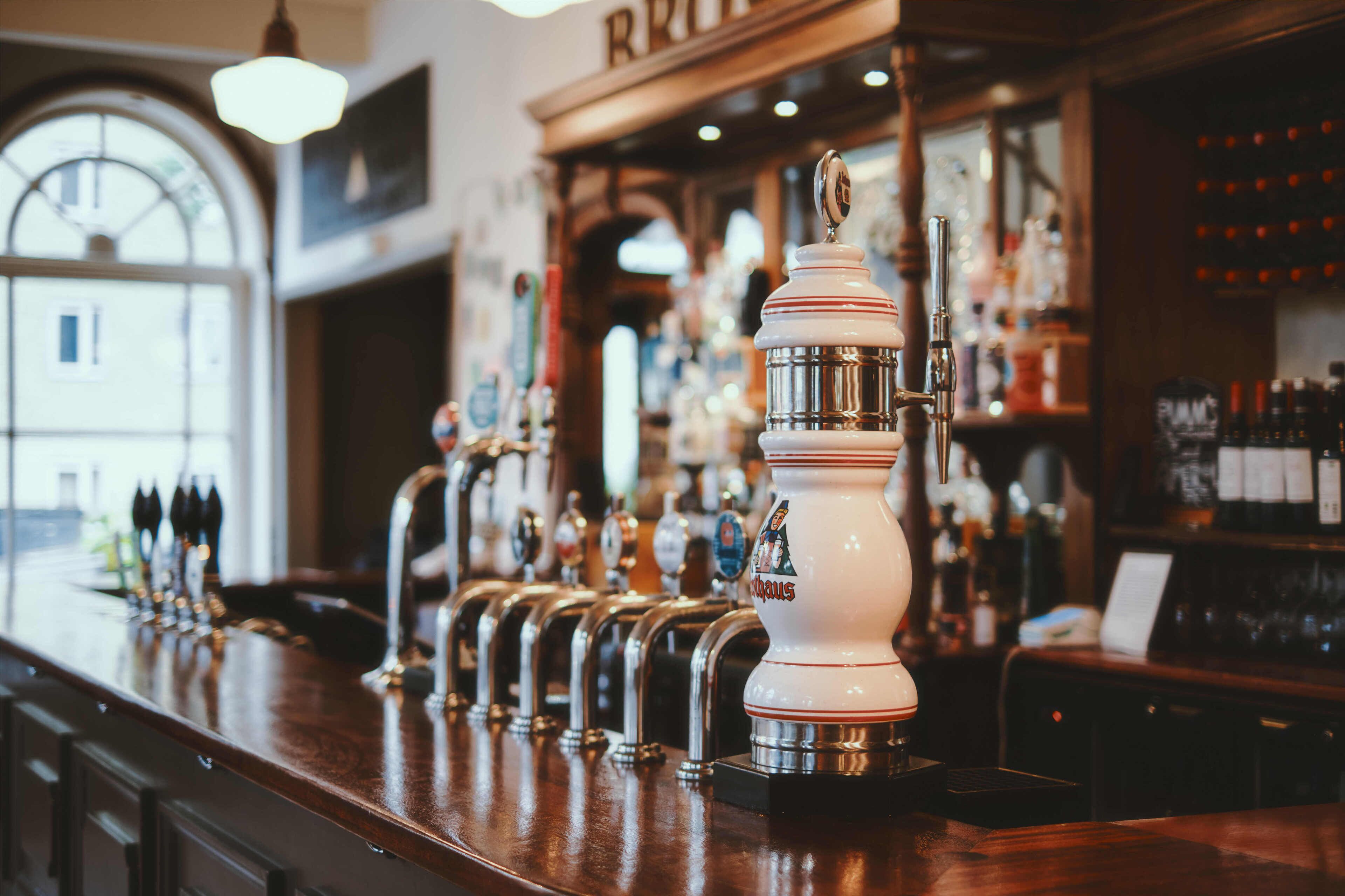 A bar with multiple beer taps and a well-stocked shelf of bottles.