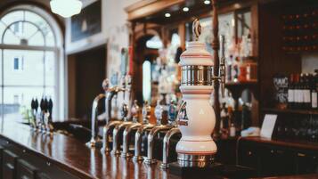 A bar with multiple beer taps and a well-stocked shelf of bottles.