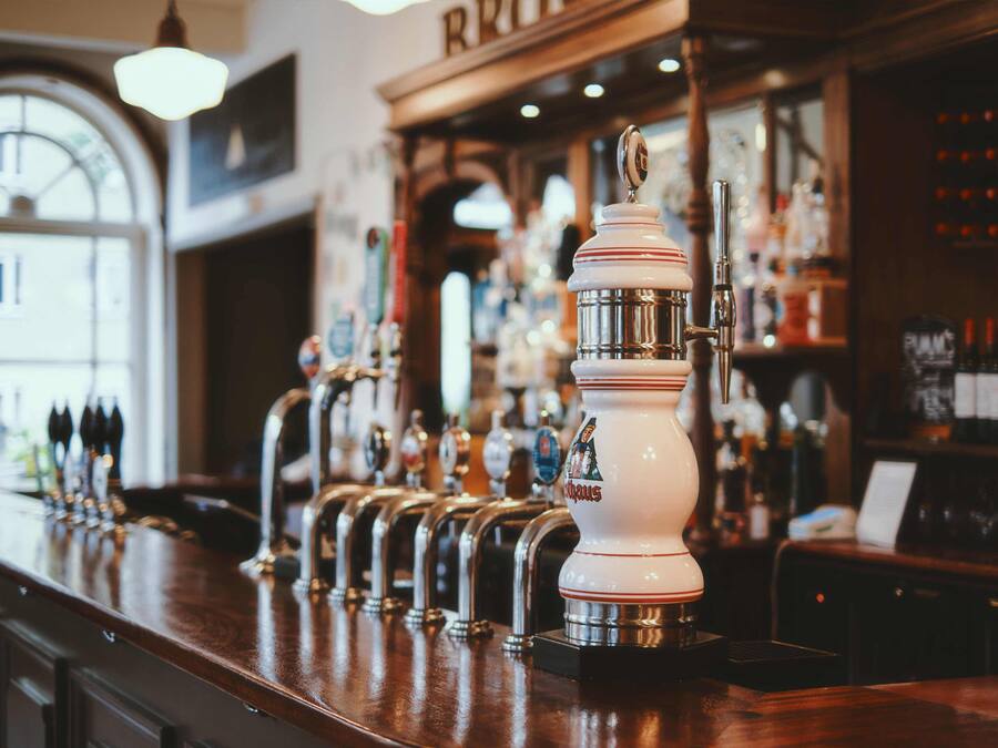 A bar with multiple beer taps and a well-stocked shelf of bottles.