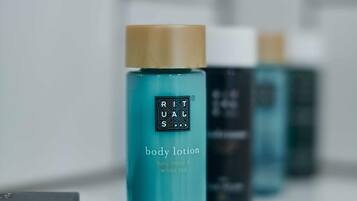 A row of body lotion bottles on a white shelf.