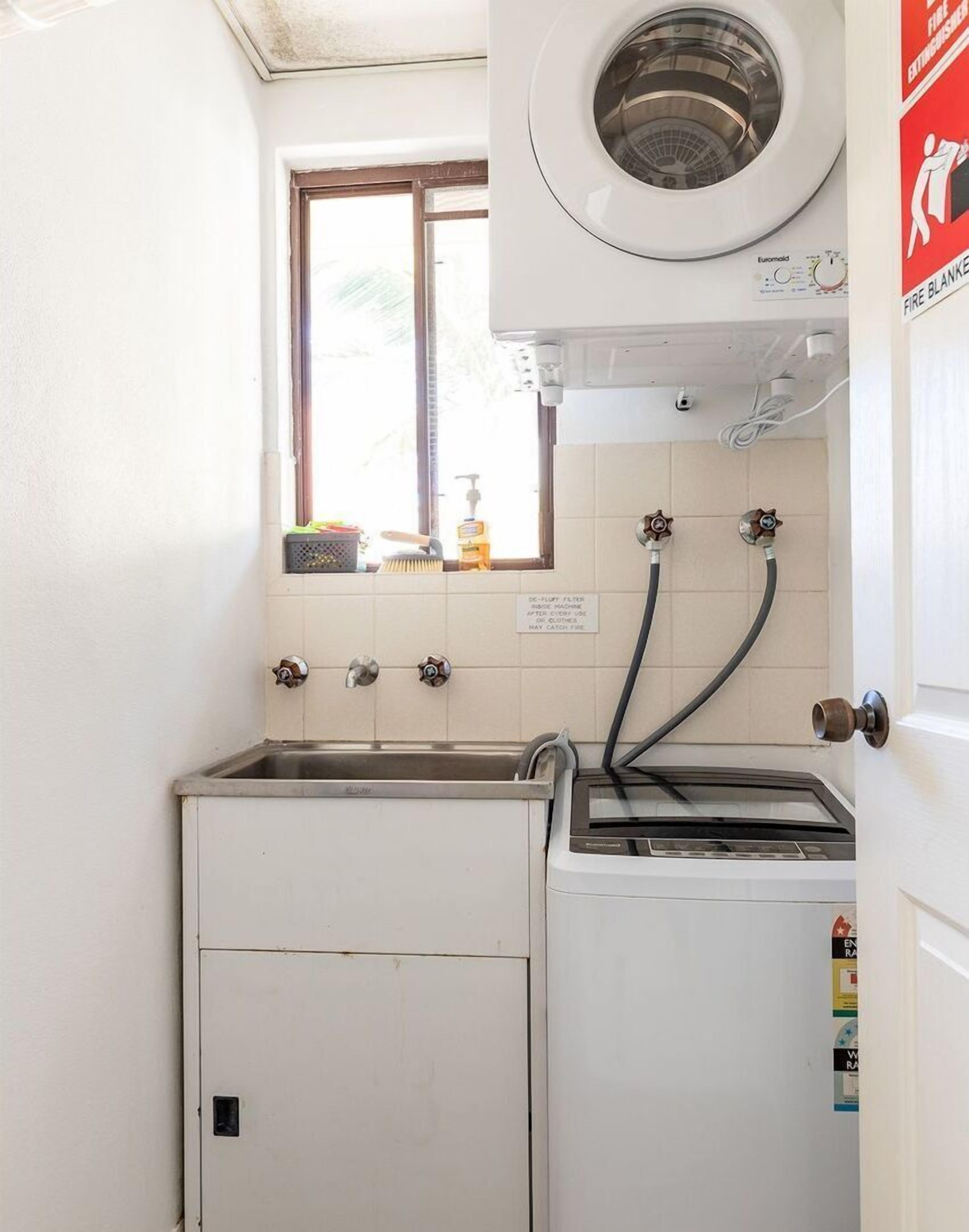A compact laundry room with a washing machine, a dryer, and a window above the washing machine.