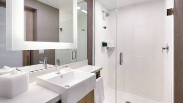 Un baño moderno con dos lavamanos, un espejo grande y una ducha con cerramiento de vidrio.