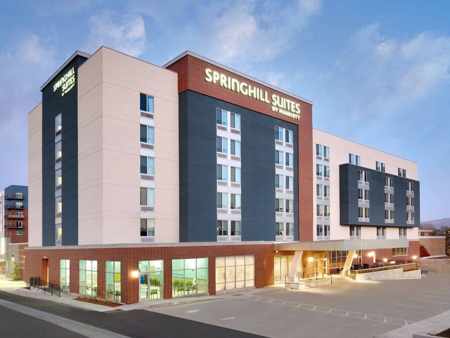 A modern hotel with a prominent sign for Springhill Suites by Marriott, featuring a brick facade, large windows, and a spacious entrance area.