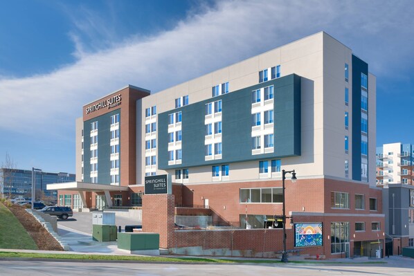 Guests enter the hotel via a covered walkway, with a parking area nearby.