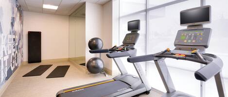 A fitness room with treadmills, a stationary bike, and exercise balls.