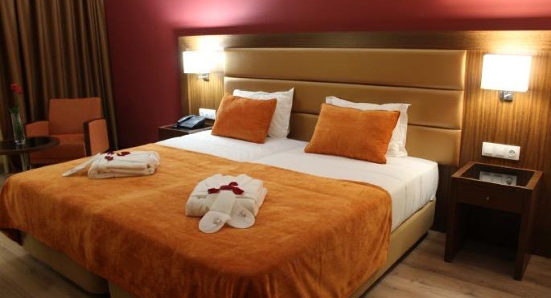 Habitación de hotel con una cama grande, dos mesitas de noche, una silla y un escritorio.