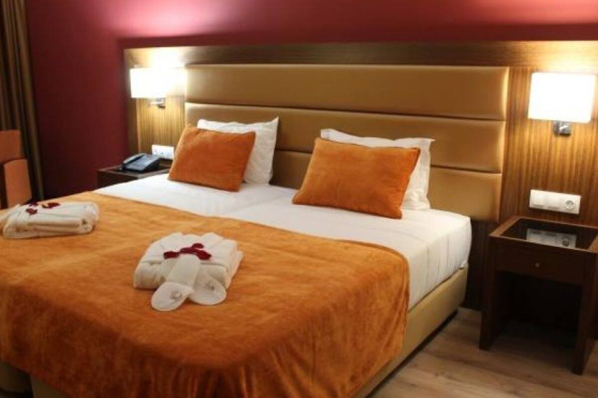 Habitación de hotel con una cama grande, dos mesitas de noche, una silla y un escritorio.